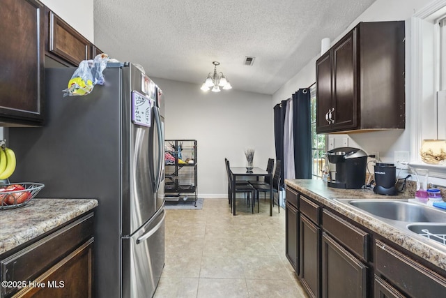 kitchen featuring visible vents, dark brown cabinetry, a textured ceiling, and a chandelier