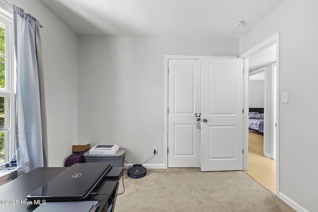 carpeted office space featuring baseboards and a textured ceiling