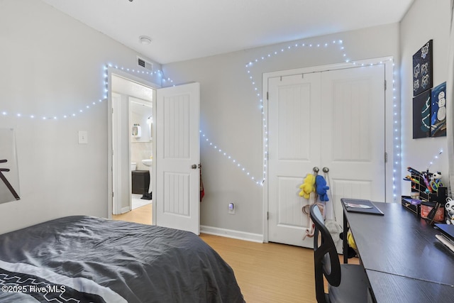 bedroom with light wood-style floors, visible vents, and a closet