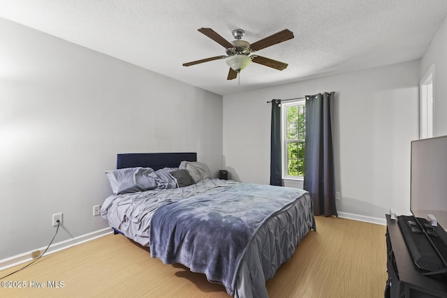 bedroom featuring a textured ceiling, baseboards, and light wood finished floors