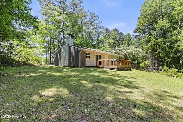 back of house with a lawn, a wooden deck, and a chimney