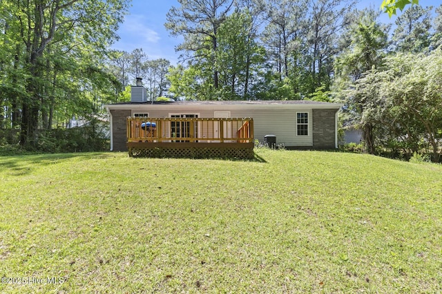 back of house featuring a lawn, a chimney, and a deck