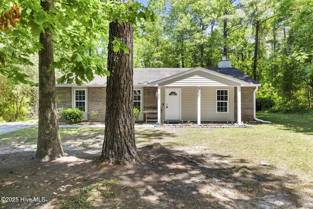 single story home featuring covered porch, a chimney, a front yard, and brick siding