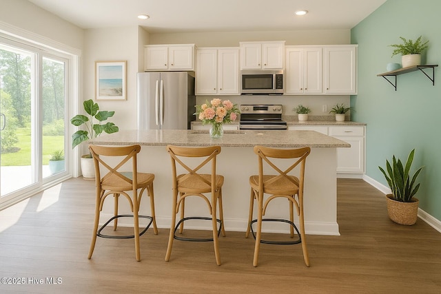 kitchen with appliances with stainless steel finishes, plenty of natural light, light wood-style flooring, and white cabinetry