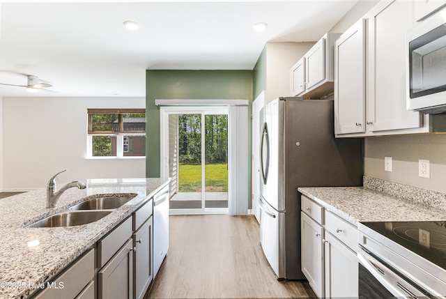 kitchen featuring light wood-style floors, stainless steel electric range, light stone counters, a sink, and dishwasher
