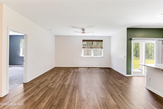 empty room featuring baseboards, ceiling fan, and dark wood-style floors