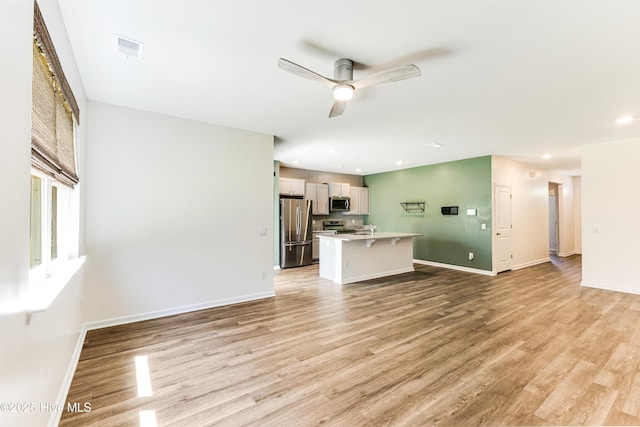 unfurnished living room with light wood finished floors, a ceiling fan, baseboards, recessed lighting, and visible vents