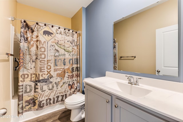 bathroom with vanity, toilet, wood finished floors, and shower / tub combo with curtain
