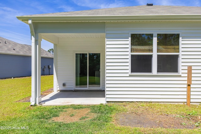 rear view of house featuring a patio, a shingled roof, and a yard