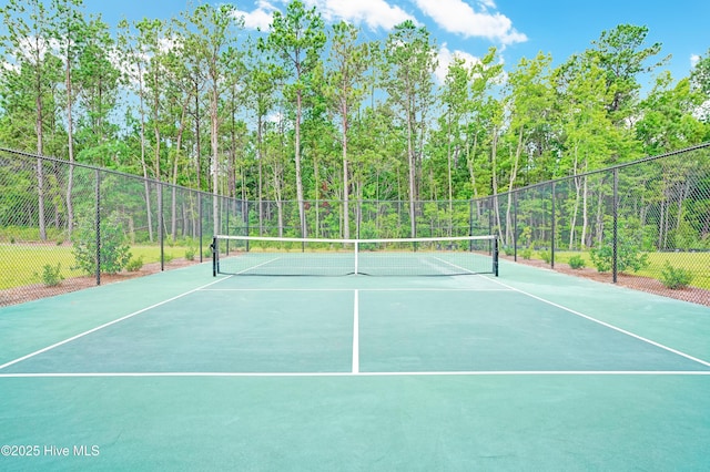 view of sport court featuring fence, community basketball court, and a forest view