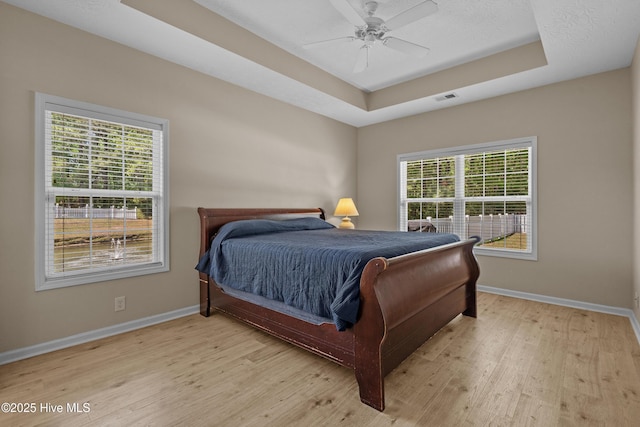 bedroom featuring baseboards, visible vents, multiple windows, and light wood-style floors