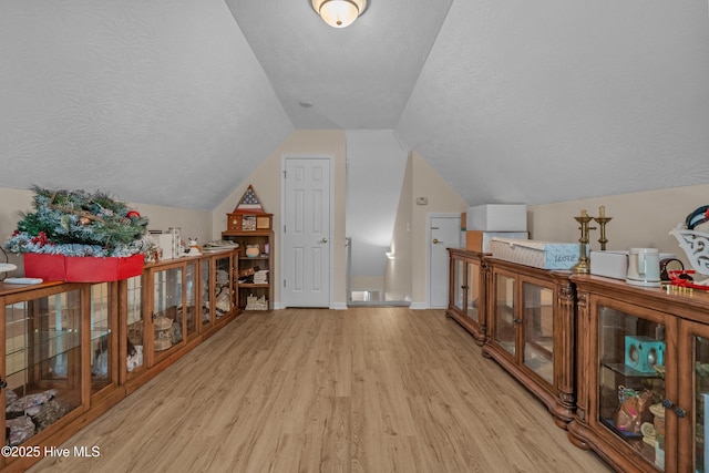 bonus room featuring a textured ceiling, baseboards, wood finished floors, and lofted ceiling