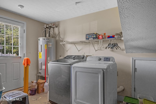 washroom featuring water heater, a textured ceiling, laundry area, and independent washer and dryer