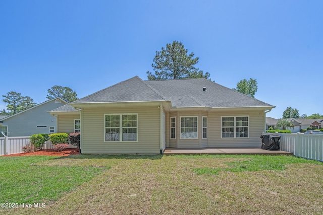 back of property featuring a fenced backyard, a shingled roof, and a lawn