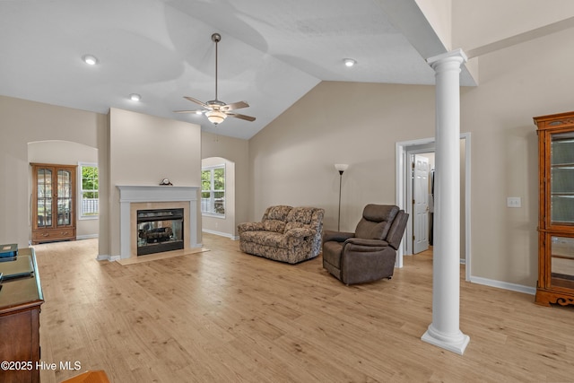 living room with a multi sided fireplace, plenty of natural light, light wood-type flooring, and ornate columns