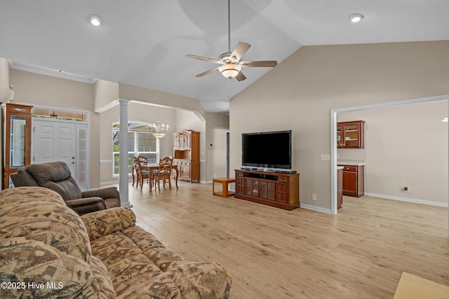 living room featuring baseboards, high vaulted ceiling, ornate columns, light wood finished floors, and ceiling fan with notable chandelier