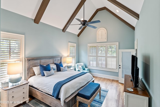 bedroom with high vaulted ceiling, beamed ceiling, multiple windows, wood finished floors, and a ceiling fan