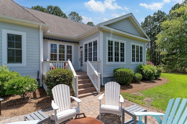 rear view of house featuring a patio area and a shingled roof
