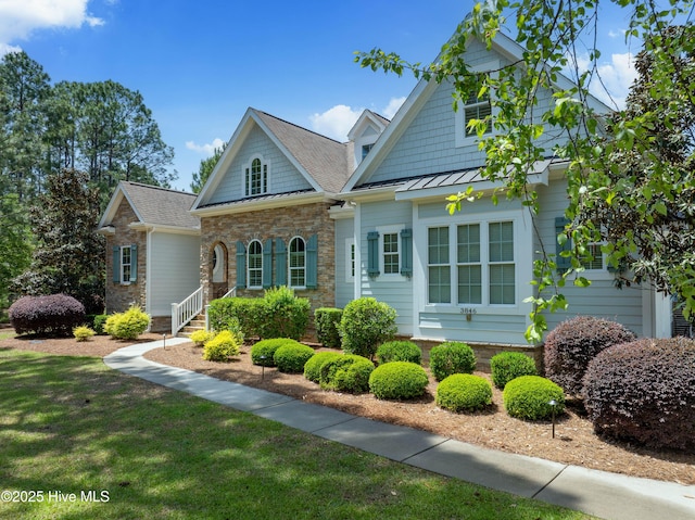 craftsman-style home with stone siding, a front lawn, a standing seam roof, and a shingled roof