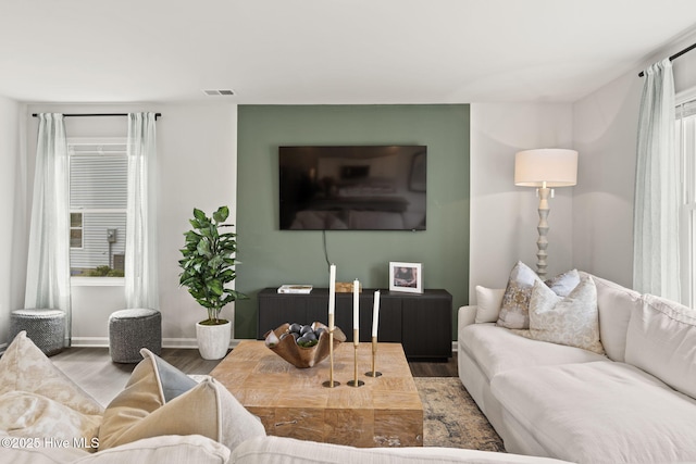 living area with baseboards, wood finished floors, and visible vents