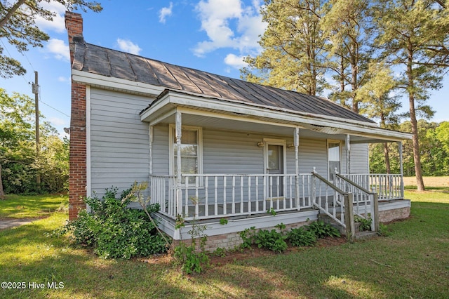 bungalow-style home with a chimney, covered porch, and a front yard