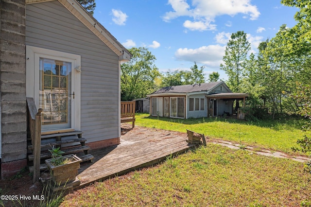 view of yard with entry steps, a wooden deck, and a sunroom