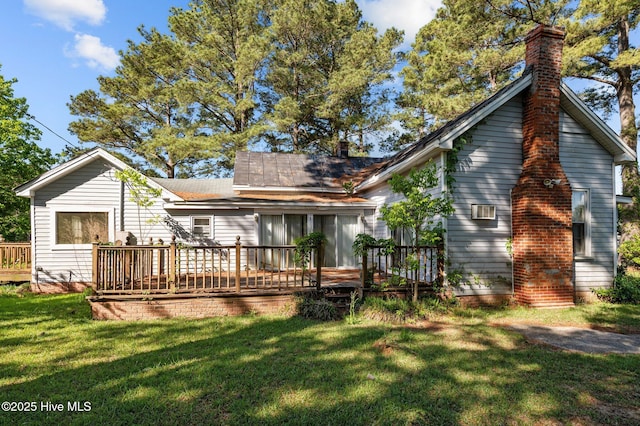 rear view of property featuring a chimney, a yard, and a deck