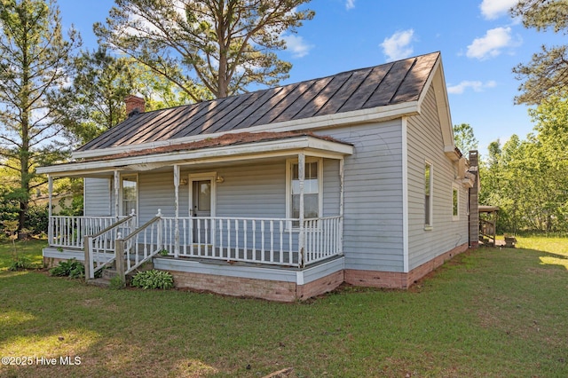 bungalow-style house featuring a standing seam roof, a chimney, a porch, and a front yard