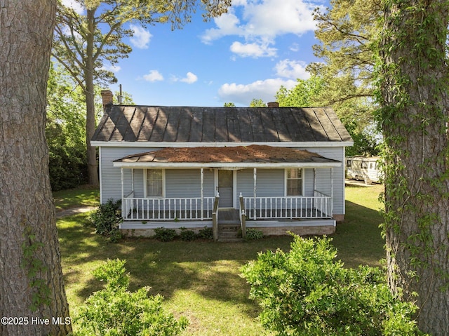 view of front facade with covered porch, a chimney, and a front lawn