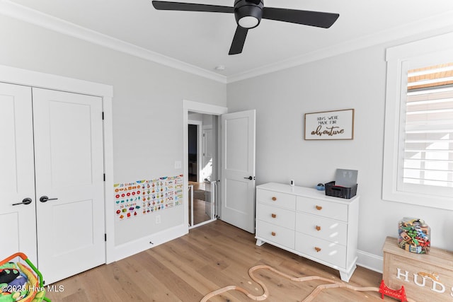 bedroom with ceiling fan, light wood finished floors, baseboards, ornamental molding, and a closet