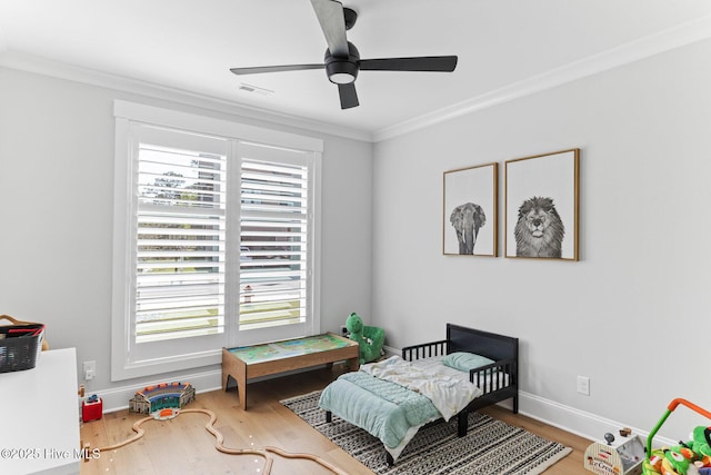 bedroom with ceiling fan, baseboards, wood finished floors, visible vents, and ornamental molding