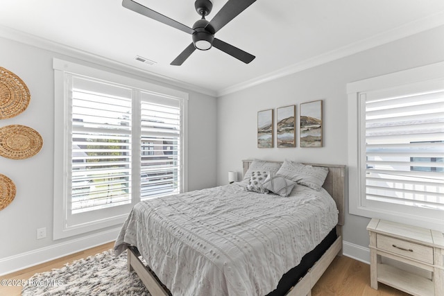 bedroom featuring crown molding, baseboards, visible vents, and light wood-style floors