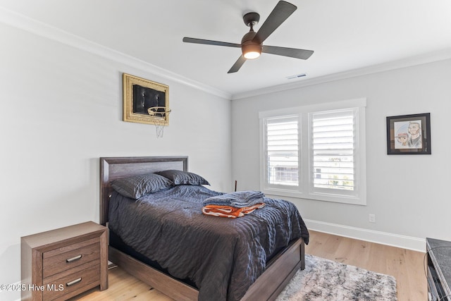bedroom with ceiling fan, visible vents, light wood-type flooring, baseboards, and ornamental molding