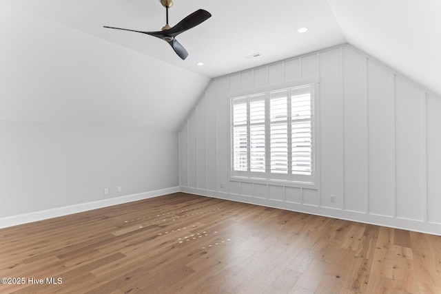 bonus room featuring a decorative wall, wood-type flooring, a ceiling fan, and lofted ceiling