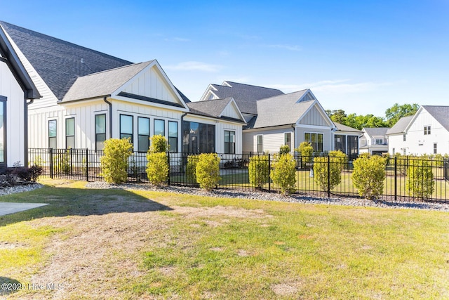back of property featuring a shingled roof, fence, board and batten siding, and a lawn