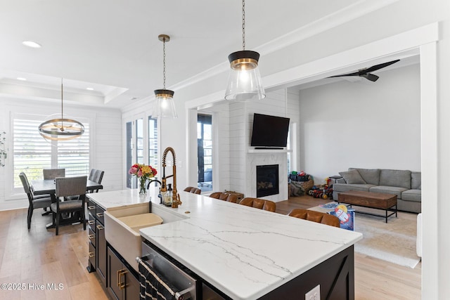 kitchen featuring a fireplace, decorative light fixtures, ornamental molding, and light wood-style floors