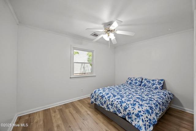 bedroom with visible vents, crown molding, wood finished floors, baseboards, and ceiling fan