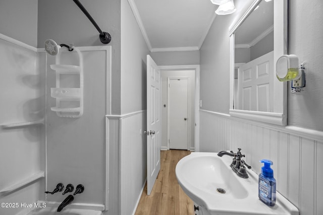 full bath featuring ornamental molding, wainscoting, wood finished floors, and shower / bathing tub combination