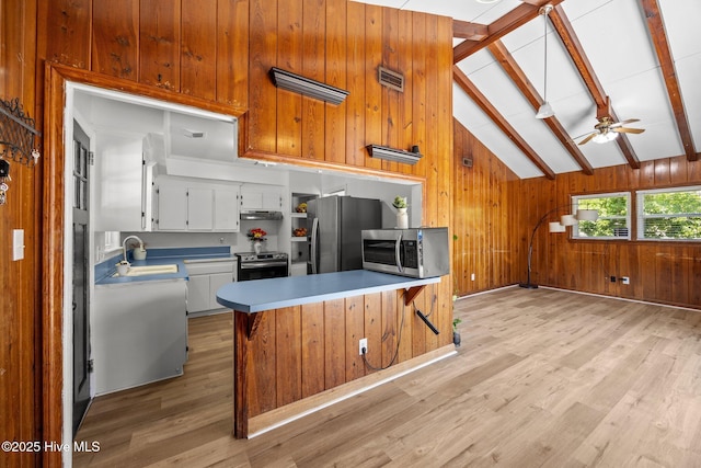 kitchen with visible vents, wood walls, a sink, stainless steel appliances, and light wood-style flooring