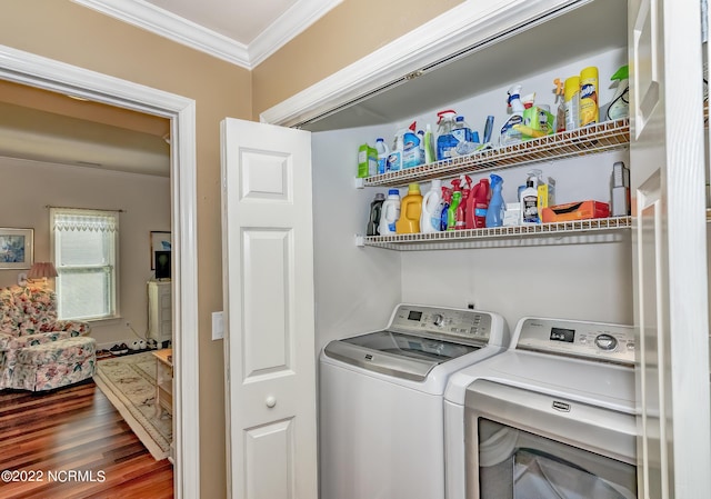 laundry room featuring ornamental molding, laundry area, wood finished floors, and washing machine and clothes dryer