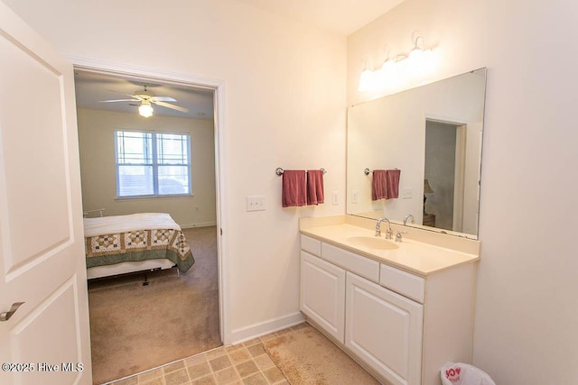 ensuite bathroom featuring a ceiling fan, vanity, and baseboards