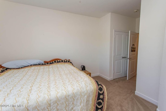 bedroom with light colored carpet and baseboards