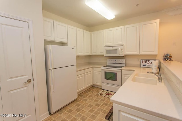 kitchen with white appliances, a sink, white cabinets, light floors, and light countertops