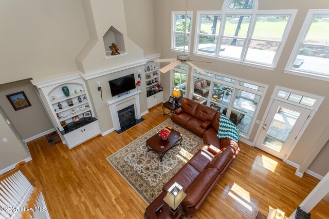 84 Deerwood Ln, Pinehurst, NC 28374 - living area with a fireplace with flush hearth, a ceiling fan, light wood-style flooring, and a towering ceiling