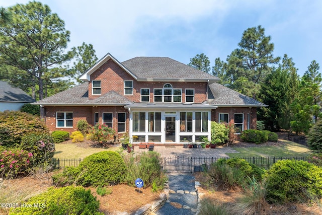 84 Deerwood Ln, Pinehurst, NC 28374 - rear view of house featuring brick siding, a shingled roof, fence private yard, and a sunroom