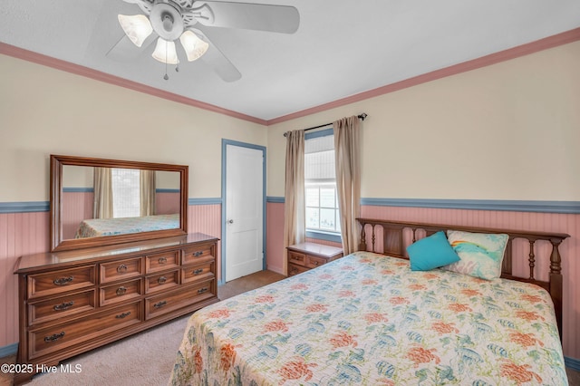 bedroom with carpet floors, a ceiling fan, crown molding, and wainscoting