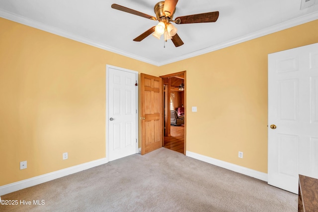 unfurnished bedroom with a ceiling fan, visible vents, carpet floors, baseboards, and ornamental molding
