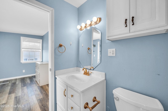 bathroom featuring toilet, baseboards, wood finished floors, and vanity