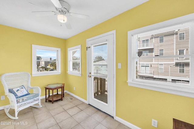 doorway featuring baseboards, a ceiling fan, light tile patterned flooring, and visible vents