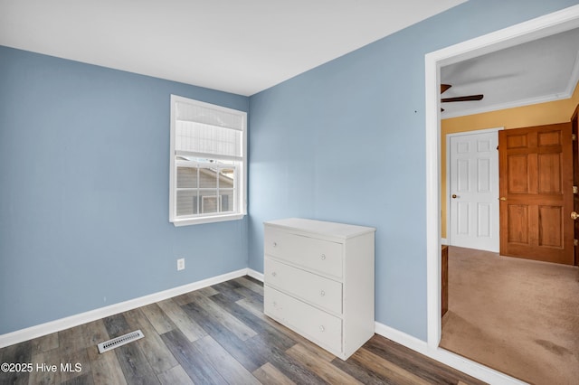 unfurnished bedroom featuring baseboards, wood finished floors, and visible vents